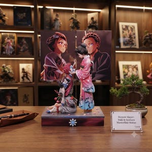 Könnte beinhalten: Eine Demon Slayer Daki und Gyutaro Masterline-Statue mit zwei Figuren auf einem rechteckigen Sockel und einer Hintergrundplatte. Die weibliche Figur trägt einen rosa-blauen Kimono, die männliche kniet. Ein Schild trägt die Aufschrift Demon Slayer: Daki & Gyutaro Masterline Statue.