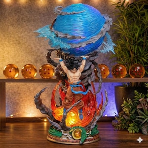May include: A detailed figurine of a Dragon Ball Z character, with a blue energy sphere above. The figure is in a dynamic pose, surrounded by fiery effects. The base has a dragon design, and several glowing orbs are on a shelf in the background.