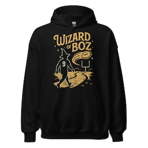 Może przedstawiać: Czarna bluza z kapturem ze złotą grafiką. Grafika przedstawia napis "Wizard of Boz" nad ilustracją czarodzieja idącego po żółtej ceglanej drodze w kierunku piłki nożnej i słupków bramki. Czarodziej ma spiczasty kapelusz i numer 9.