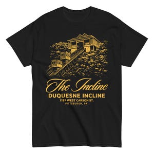 May include: Black t-shirt with a gold illustration of the Duquesne Incline, a funicular railway, and the text "The Incline" and address details. The design shows the incline cars and the station at the top of the hill.