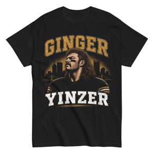 May include: Black t-shirt with a graphic of a man with a mustache and long hair, and the words "GINGER YINZER" in gold and white. A cityscape is visible in the background of the design.