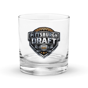 May include: A clear glass tumbler with a printed logo for the Pittsburgh Draft 2026. The logo is a shield shape with the words "Pittsburgh Draft" in a bold, stylized font. The logo also includes a football and the year 2026.