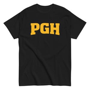 以下が含まれることがあります： 胸に黄色の文字「PGH」が入った黒いTシャツ。文字は太字のブロックフォントです。シャツは半袖で、クルーネックです。