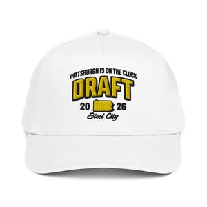 Puede incluir: Gorra de béisbol blanca con el texto "PITTSBURGH IS ON THE CLOCK DRAFT 2026 Steel City" en negro y amarillo. La gorra tiene una visera curva y una corona estructurada.