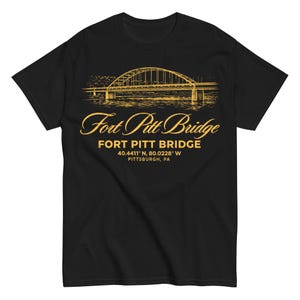 Peut inclure: T-shirt noir avec une illustration dorée du pont Fort Pitt. Le texte "Fort Pitt Bridge" est affiché dans une police stylisée, avec le nom et les coordonnées du pont en dessous. Un design classique pour les fans de Pittsburgh.