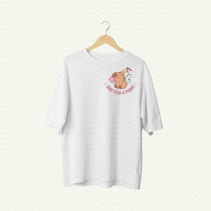 May include: White t-shirt with a cartoon illustration of a brown animal wearing a party hat and fairy wings. The text "See you're a fairy" is printed below the illustration.