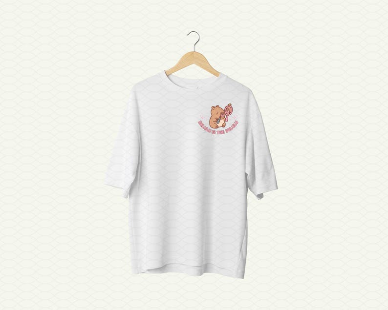 May include: White t-shirt with a brown bear holding a pink flower and the text "Honey in the Wild" printed on the front.
