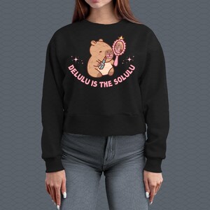 May include: Black cropped sweatshirt with a cartoon capybara wearing lipstick and looking in a mirror. The text "Delulu is the Solulu" is printed on the sweatshirt.