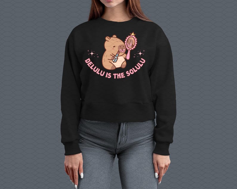 May include: Black cropped sweatshirt with a cartoon capybara wearing lipstick and looking in a mirror. The text "Delulu is the Solulu" is printed on the sweatshirt.