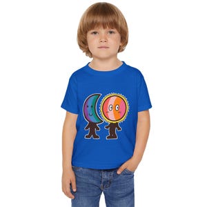 May include: A blue toddler t-shirt featuring a colorful cartoon sun and moon design. The sun has a pink and orange face with a yellow outline, and the moon has a rainbow gradient. The shirt is made of soft material.