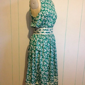 May include: A green and white floral print dress with a white trim around the neckline and hem. The dress has a fitted bodice and a full skirt.