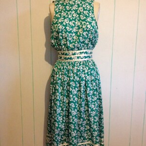 May include: A sleeveless green and white floral dress with a white ribbon around the waist.