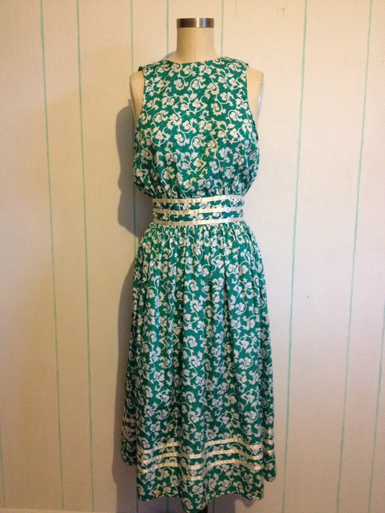 May include: A sleeveless green and white floral dress with a white ribbon around the waist.