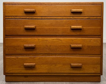 Puede incluir: Una cómoda de madera con cuatro cajones horizontales con un acabado de veta de madera marrón claro natural. Cada cajón está equipado con dos tiradores de madera rectangulares colocados simétricamente en los lados izquierdo y derecho.