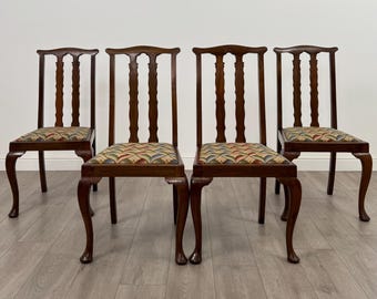 May include: Four antique wooden chairs with curved legs and patterned seat cushions. The chairs have a dark brown finish and a traditional design, suitable for a dining room or living space. The seat cushions feature a colorful, geometric pattern.