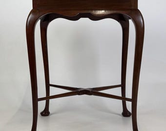 May include: A dark brown wooden side table featuring a square top with slightly curved edges, four slender cabriole legs, and a central X-shaped stretcher connecting the legs. The table stands on four rounded feet, showcasing a smooth finish.