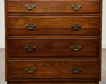Puede incluir: Una cómoda de madera con un acabado de veta marrón intenso y cuatro cajones horizontales. Cada cajón está equipado con dos tiradores de metal en tono latón, lo que proporciona una apariencia funcional y simétrica al mueble.