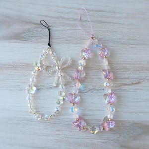 May include: Two crystal butterfly charm necklaces. One necklace is made with clear crystals and the other is made with pink and clear crystals.