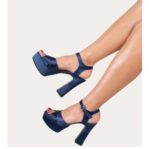 May include: A pair of navy blue satin platform sandals with a chunky heel and an ankle strap.