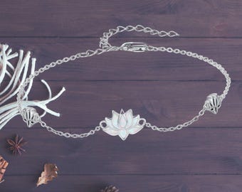 May include: A silver chain anklet with a white opal lotus flower charm. The anklet has a lobster clasp closure.