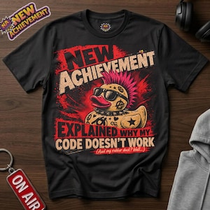May include: A black short-sleeved t-shirt featuring a graphic of a punk rubber duck with a pink mohawk, sunglasses, and a spiked collar. The text reads NEW ACHIEVEMENT EXPLAINED WHY MY CODE DOESN'T WORK (And my rubber duck? Well....).