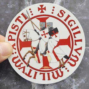 Puede incluir: Una pegatina circular con el sello histórico de los Caballeros Templarios, que representa a dos caballeros montados en un solo caballo. El diseño incluye una gran cruz roja, lanzas y el texto latino SIGILLVM MILITVM XPISTI en letras rojas.