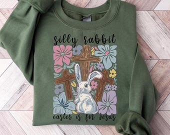 May include: Green sweatshirt with a white rabbit and crosses surrounded by flowers. The text "silly rabbit easter is for jesus" is printed on the sweatshirt.