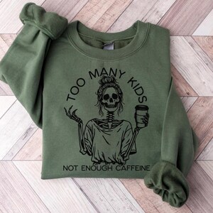 May include: Green sweatshirt with a black graphic of a skeleton holding a coffee cup. The graphic says "Too Many Kids Not Enough Caffeine".