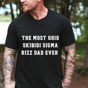 May include: Black t-shirt with white text that reads "The Most Ohio Skibidi Sigma Rizz Dad Ever".