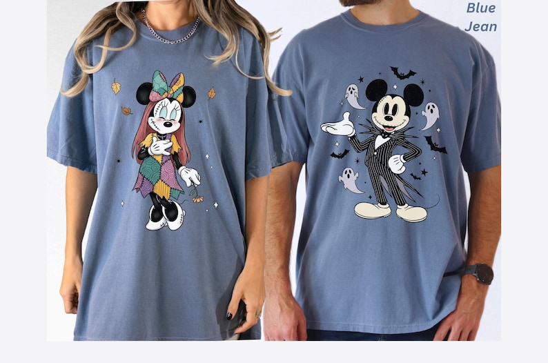May include: Two blue jean-colored t-shirts. One features Minnie Mouse in a patchwork dress with autumn leaves. The other has Mickey Mouse dressed as Jack Skellington, surrounded by bats and ghosts. Both shirts have short sleeves.