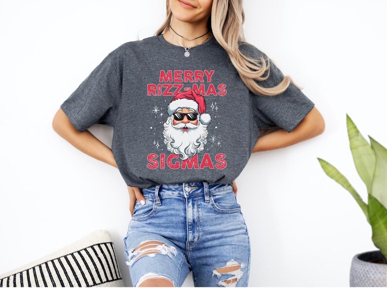 May include: A gray t-shirt with a red and white Santa Claus wearing sunglasses and the text "Merry Rizz-Mas Sigmas".