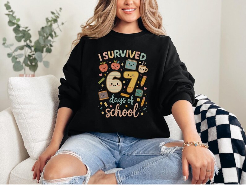 May include: Black sweatshirt with the text "I Survived 67 Days of School" in a colorful, playful design. The graphic includes smiling numbers, apples, books, and pencils, perfect for teachers or students.