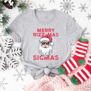 May include: A gray t-shirt with a red and white Santa Claus graphic and the text "Merry Rizzmas Sigmas".
