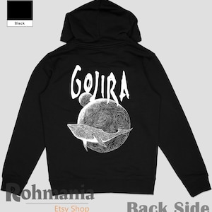 May include: Black hoodie with a white graphic on the back. The graphic features the word "Gojira" above a detailed illustration of a whale swimming around a planet. The hoodie has a hood and a front zipper.
