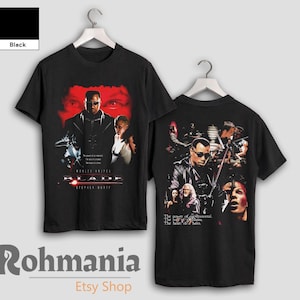 May include: Black t-shirt featuring a graphic print of the film "Blade" starring Wesley Snipes and other characters. The text "The power of an immortal. The lust of a human. The heart of a hero." is printed on the shirt.