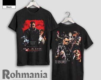 May include: Black t-shirt with a graphic print of the movie "Blade" featuring Wesley Snipes and other characters. The text "The power of an immortal. The lust of a human. The heart of a hero." is printed on the shirt.