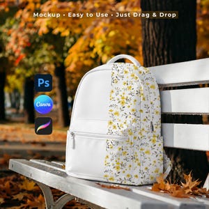 May include: A white backpack featuring a floral pattern with yellow flowers and grey leaves on the right side. The backpack includes a front zippered pocket and side pockets. Text at the top reads: Mockup - Easy to Use - Just Drag & Drop.