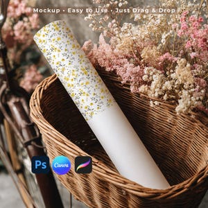 May include: A rolled-up floral patterned paper, featuring yellow flowers and gray leaves on a white background, rests in a wicker basket filled with pink and white flowers. The text "Mockup • Easy to Use • Just Drag & Drop" is visible.