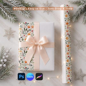 Könnte beinhalten: Eine rechteckige Geschenkbox, eingewickelt in weißes Papier mit einem botanischen Muster aus Orangen und grünen Blättern, gebunden mit einem blass pfirsichfarbenen Satinband. Daneben liegt eine passende Rolle Geschenkpapier. Text: Mockup • Easy to Use • Just Drag & Drop.