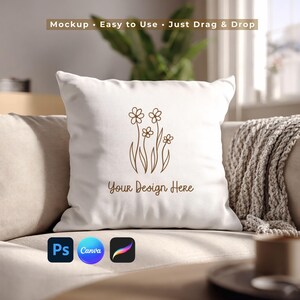 May include: A white square pillow with a brown floral design and the text "Your Design Here." The pillow is on a beige sofa. The top of the image has the text "Mockup • Easy to Use • Just Drag & Drop." Below the pillow are the logos for Photoshop, Canva, and Procreate.