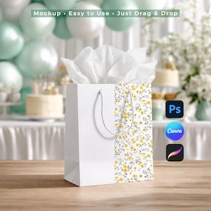 May include: White gift bag with a floral pattern of yellow flowers and green leaves. The bag has a white rope handle and is filled with white tissue paper. The text "Mockup • Easy to Use • Just Drag & Drop" is visible.