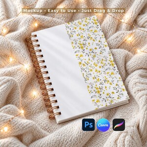 May include: A spiral-bound notebook featuring a white cover with a vertical floral pattern of small yellow flowers and grey stems on the right side. The notebook has a copper-colored metal wire binding along the left edge. Text reads Mockup Easy to Use Just Drag & Drop.