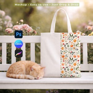 May include: A white tote bag with a floral design featuring oranges and leaves. The bag is sitting on a white bench with a sleeping orange tabby cat. The text "Mockup • Easy to Use • Just Drag & Drop" is visible.