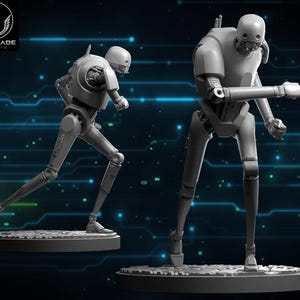 Puede incluir: Dos figuras grises de droides K-2SO, una en pose de carrera y la otra de pie con un brazo extendido. Las figuras están sobre bases circulares. El logotipo de Wardlade Studio está en la esquina superior izquierda.