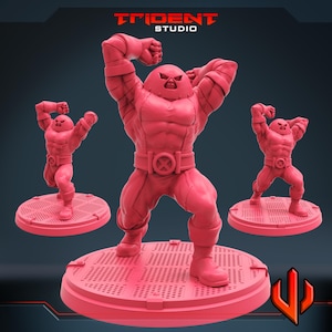 Può includere: Un set di tre action figure rosa di un personaggio muscoloso in posa dinamica. Le figure sono su basi circolari con un motivo a griglia. Il personaggio indossa un elmetto e una cintura con un simbolo "X". Il logo Trident Studio è visibile.