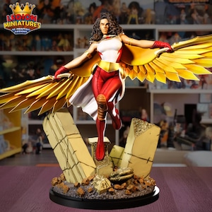 May include: A detailed figurine of a superheroine with golden wings, red and white suit, and a flowing cape. The figure is posed dynamically on a base with stylized, broken stone elements. The logo "LEGION MINIATURES 3D PRINTING DESIGNS" is visible.