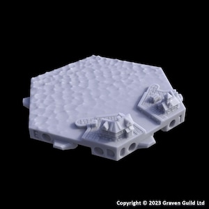 May include: A light gray, hexagonal terrain piece with a textured surface and miniature buildings. The piece has a detailed, three-dimensional design, with small structures and arched openings along the edges. The copyright notice "© 2023 Graven Guild Ltd" is visible.