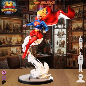 May include: A Supergirl figurine in a dynamic pose, with a red and blue costume and a flowing red cape. The figurine is mounted on a circular base with a white cloud-like effect. The text "MAY RELEASE" is visible.