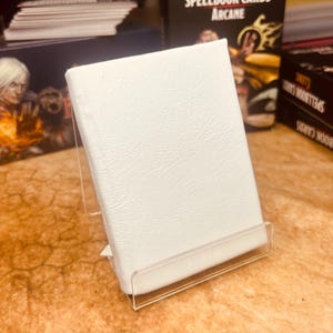 Mini livro de feitiços de couro branco com 1 encarte para D&D, Pathfinder, outros RPGs ou cartões de visita. Comporta 20 cartas.