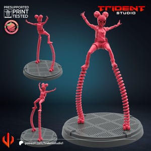 Puede incluir: Una figura rosa de un personaje con casco y piernas en forma de resorte, posando sobre una base circular. La figura está en una pose dinámica con los brazos levantados. La imagen incluye el texto "TRIDENT STUDIO" y "PRESUPPORTED PRINT TESTED".
